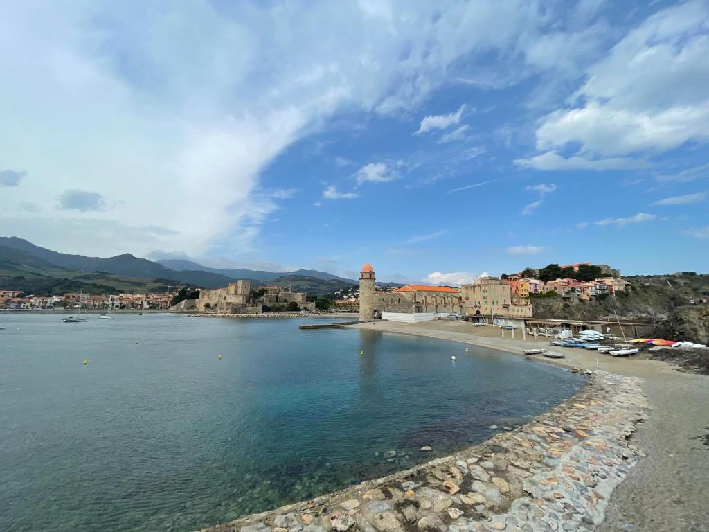 a view of a beach with a lighthouse in the water at 5COMA2 Appartement proche plage in Collioure