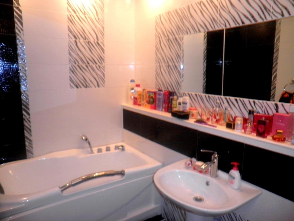 Un baño con lavabo y bañera y un lavabo. en Квартира в центре города на Арбате, en Almaty