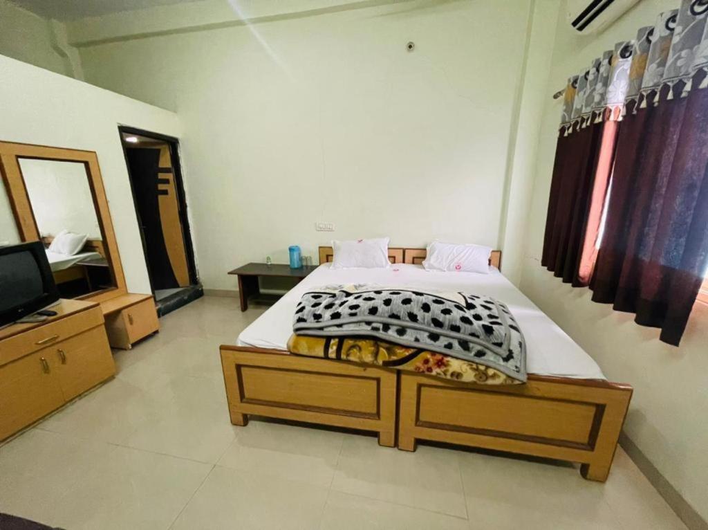 a bedroom with a large bed and a television at Hotel Aashirwad in Maheshwar