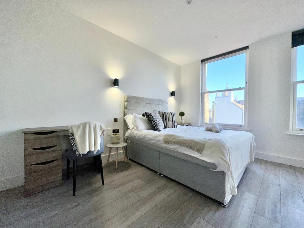 een witte slaapkamer met een bed en een raam bij Sleek Stylish 1 Bedroom Leeds City Apartment in Leeds