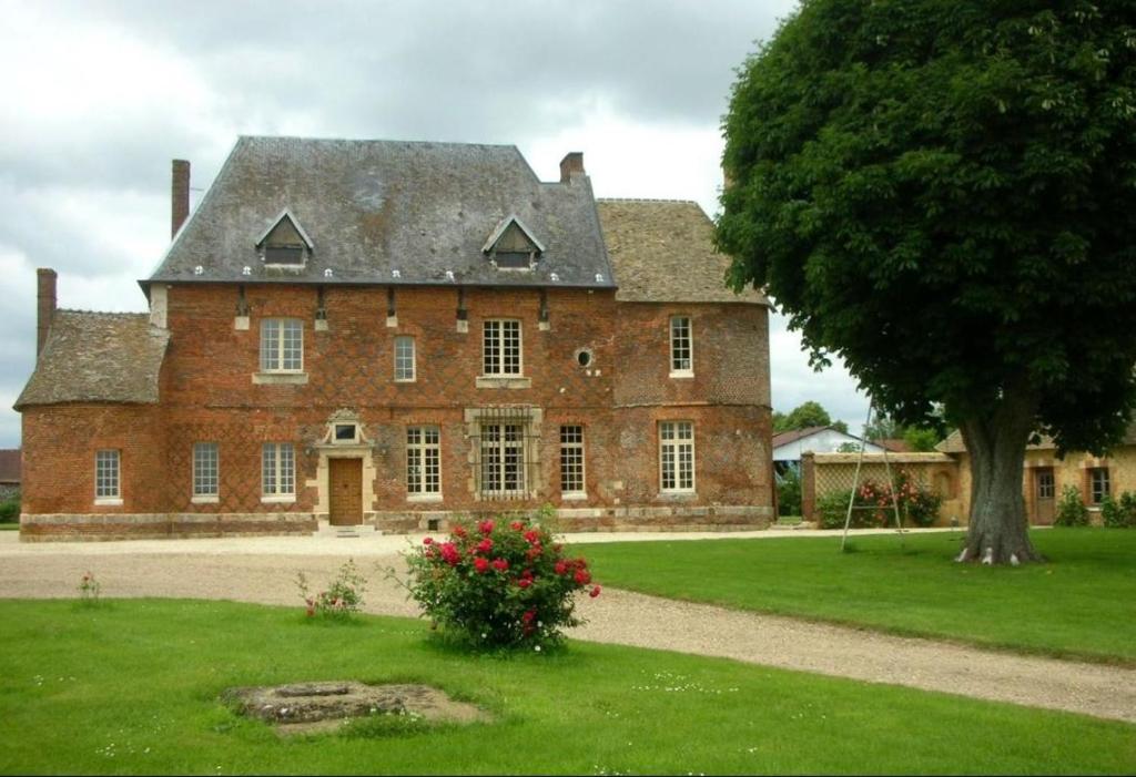 uma grande casa de tijolos com uma árvore em frente em Manoir du Petit Logis 