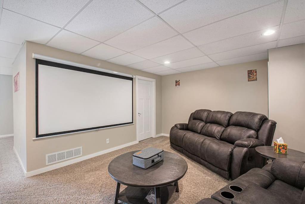 a living room with a couch and a large screen at Stylish Retreat Master Suite in Omaha