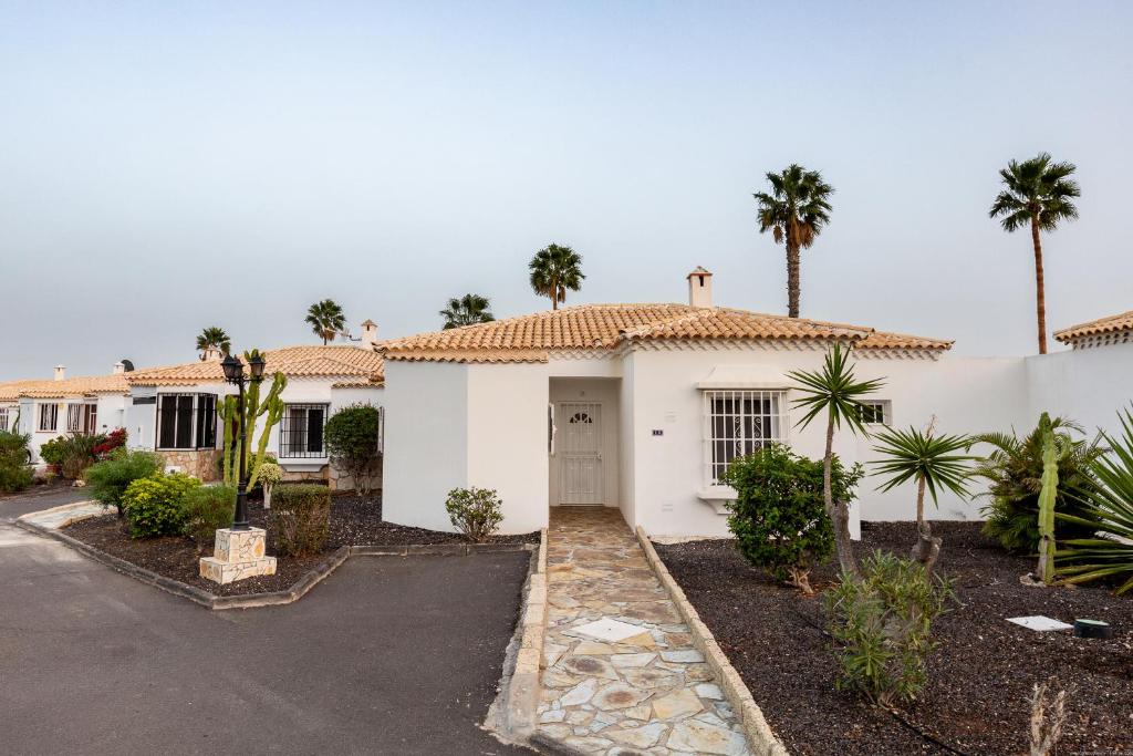 uma casa branca com palmeiras e uma entrada em Bungalow in Golf del sur em San Miguel de Abona