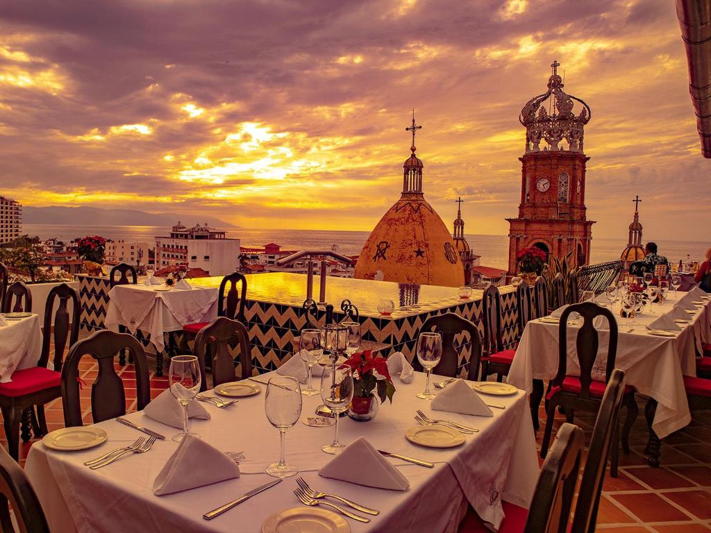 a group of tables with wine glasses and a clock tower at BellView Hotel Boutique in Puerto Vallarta