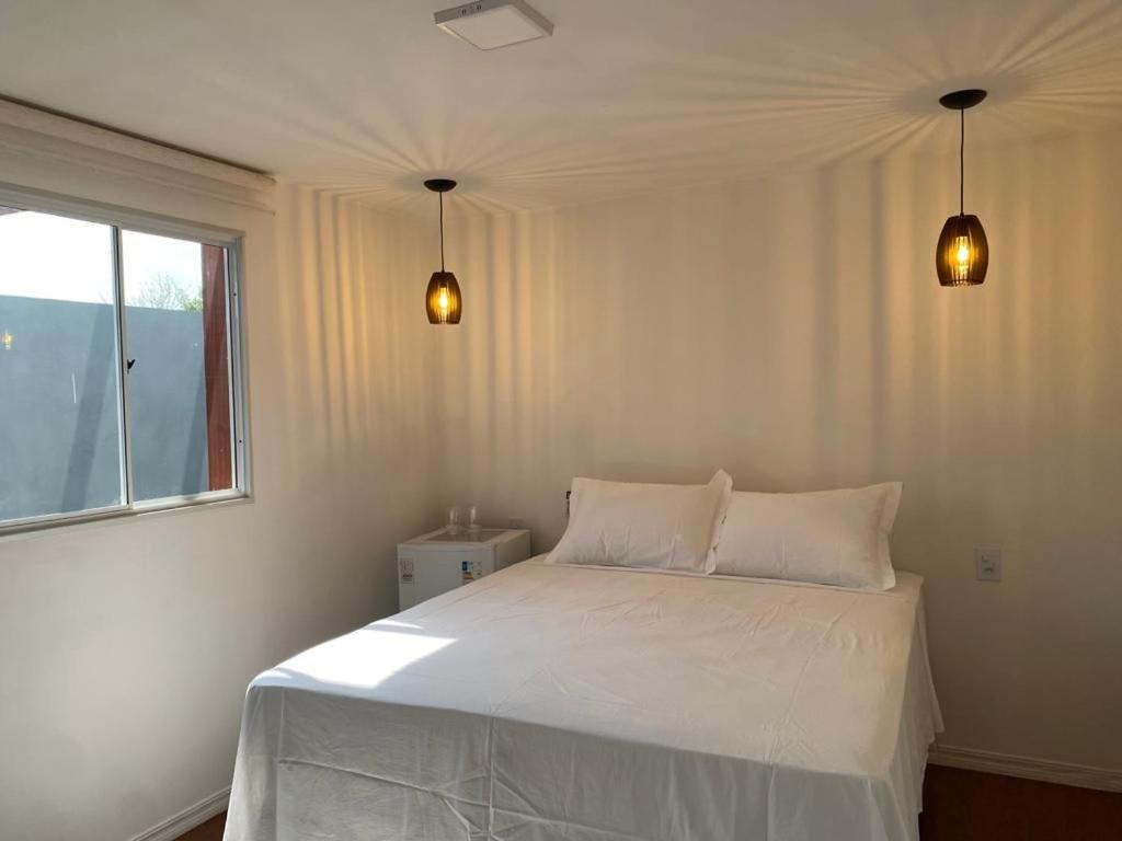 a white bed in a bedroom with two lights at Bangalô Miraflores in Chapada dos Guimarães