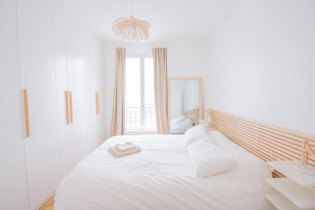 a white bedroom with a large bed with white pillows at *Cozy flat-Latin Quarter in the heart of Paris* in Paris