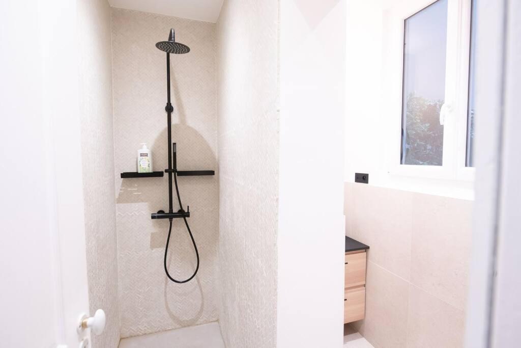 a shower in a white bathroom with a shower head at *Cozy flat-Latin Quarter in the heart of Paris* in Paris