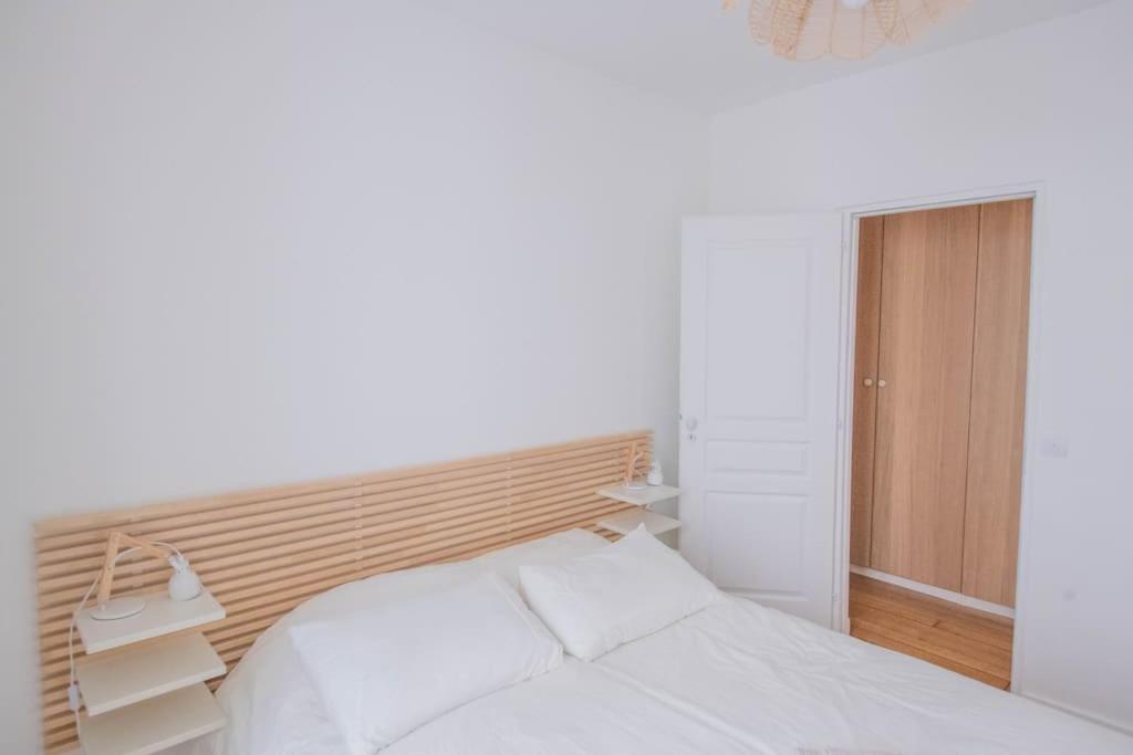 a bedroom with a white bed and a wooden headboard at *Cozy flat-Latin Quarter in the heart of Paris* in Paris