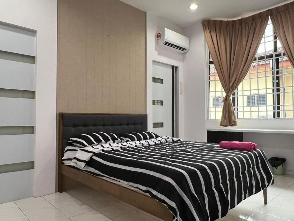 - un lit avec une couette en noir et blanc rayée dans l'établissement Muar 6 Bedrooms Semi-D With Security Guard Homestay 15-20pax, à Muar