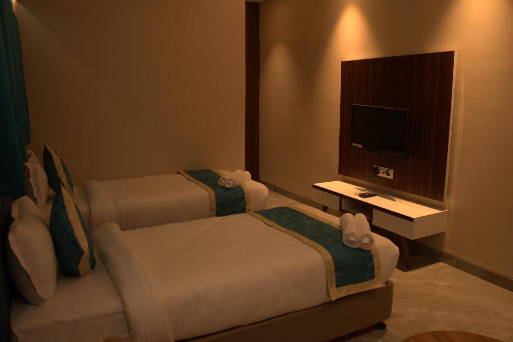 a hotel room with two beds and a television at Hotel Tanisha in Kishanganj Bazar