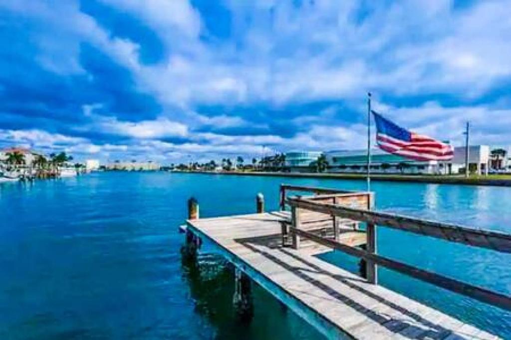 a dock with an american flag on the water at 2 Bedroom Beach Condo With Dock AND Walk To Everything in St Pete Beach