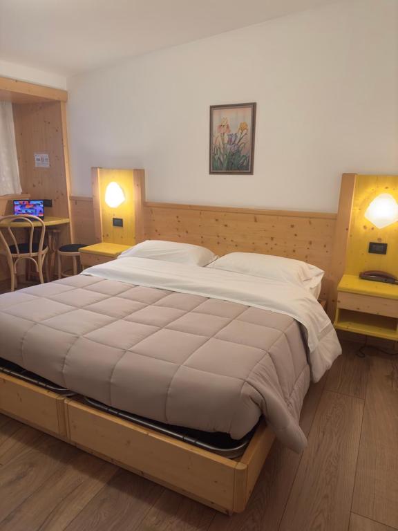 ein großes Bett in einem Schlafzimmer mit zwei eingeschalteten Lampen in der Unterkunft Hotel Zeni in Madonna di Campiglio