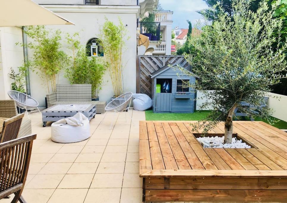 eine Terrasse mit einem Holztisch und einem Baum in der Unterkunft Logement F3 moderne, un petit paradis a Paris ! in Le Plessis-Robinson