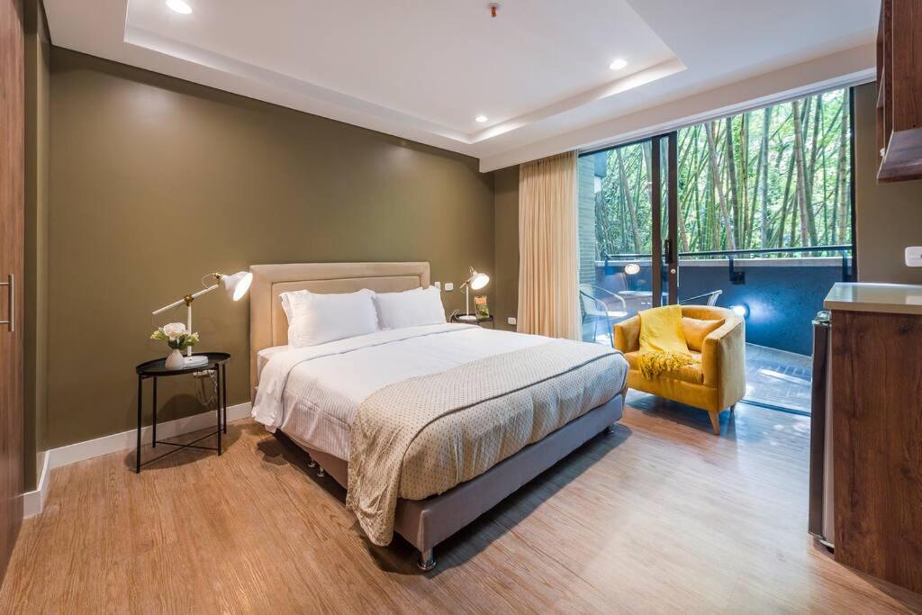 a bedroom with a large bed and a yellow chair at El Tesoro Medellín Hab315 by Letoh in Medellín