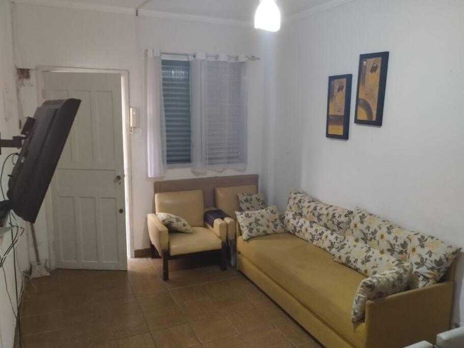 a living room with a couch and a television at Canto do Forte Apto térreo in Praia Grande
