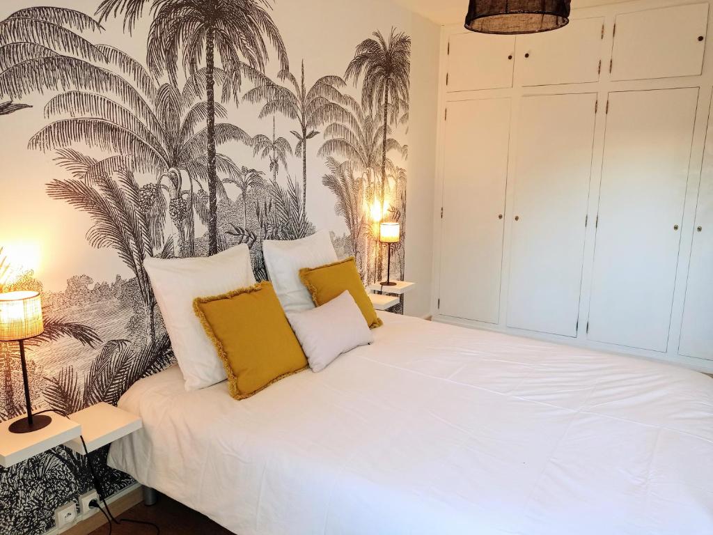 um quarto com uma cama branca e almofadas amarelas em BLEU CASSIS-VINTAGE avec 3 chambres em Cassis