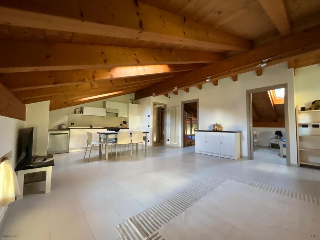 a large kitchen with wooden ceilings and a living room at L'Acero Rosso in Prosto di Piuro