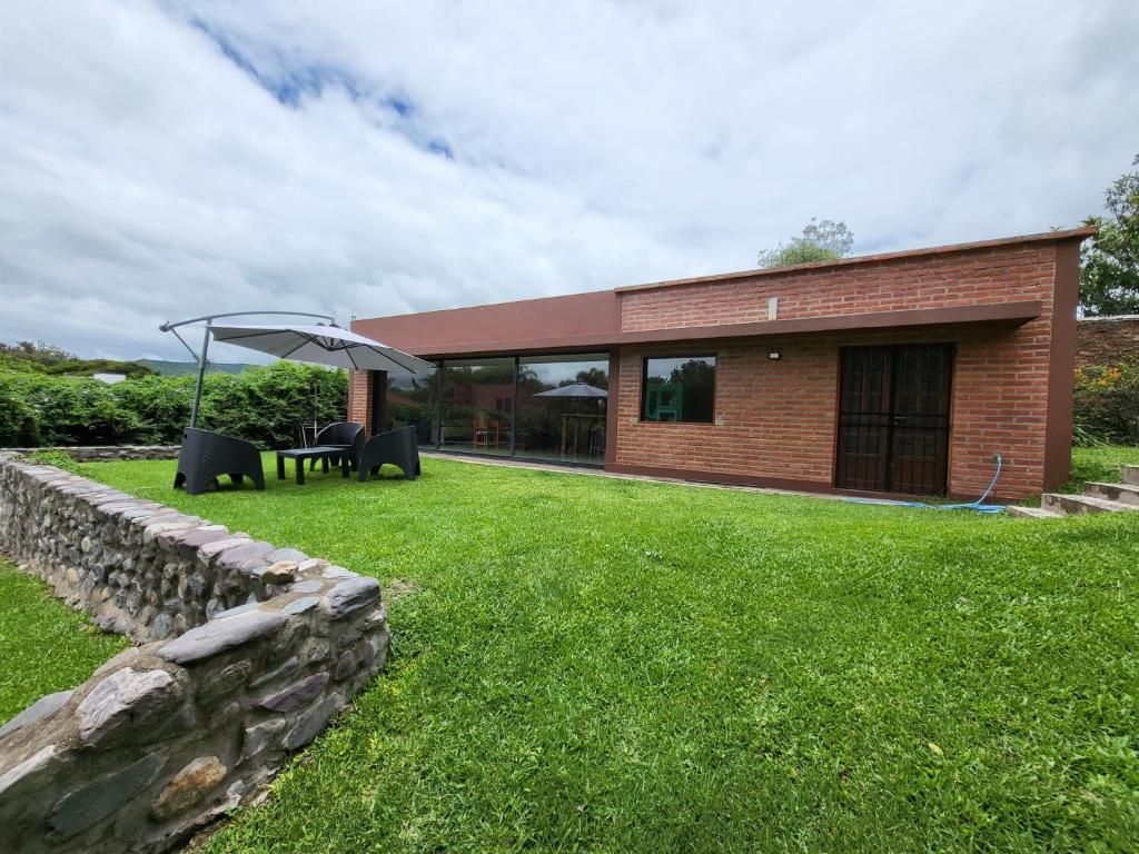 a brick house with a stone wall and an umbrella at Las Pircas 182 in San Salvador de Jujuy