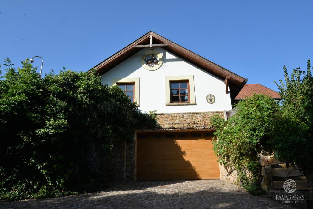 ein weißes Haus mit einer Garage und einem Fenster in der Unterkunft Pávakakas Vendégház in Vác