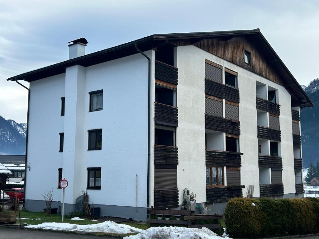 un bâtiment blanc avec un toit noir dans l'établissement Apartment Pilz, à Gosau