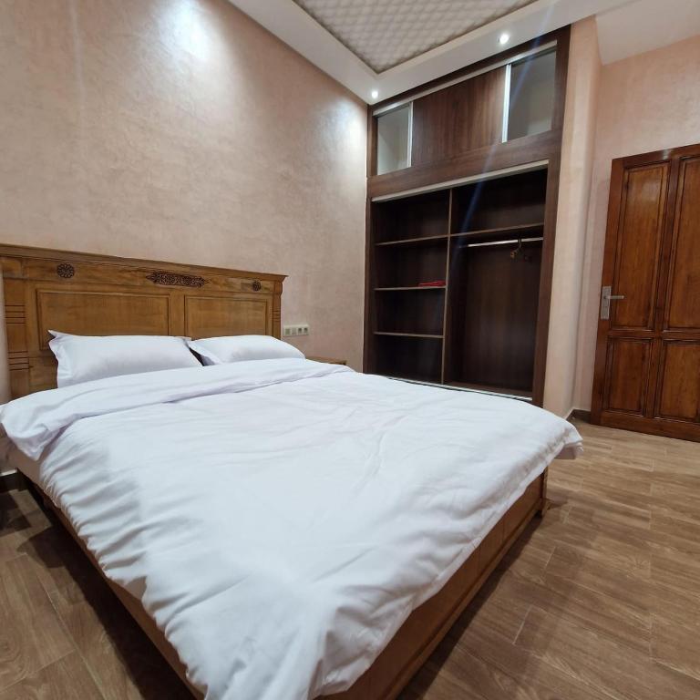 una camera da letto con un grande letto bianco con testiera in legno di Bel appartement de 2 chambres a Marrakech
