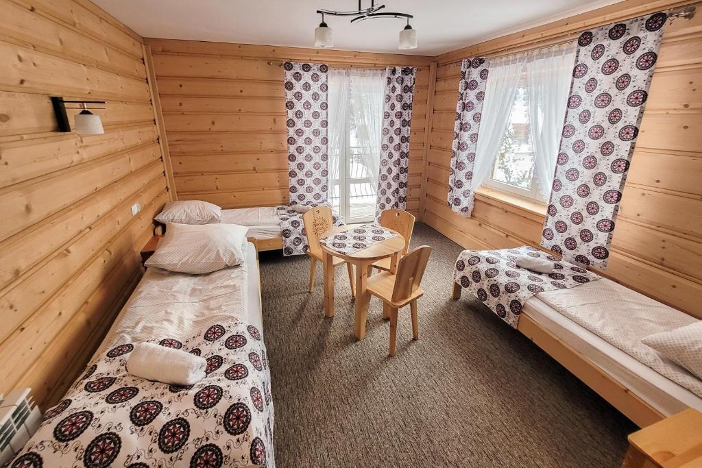 Una habitación con dos camas y una mesa dentro. en Pokoje Gosinne U Ani i Andrzeja, en Małe Ciche