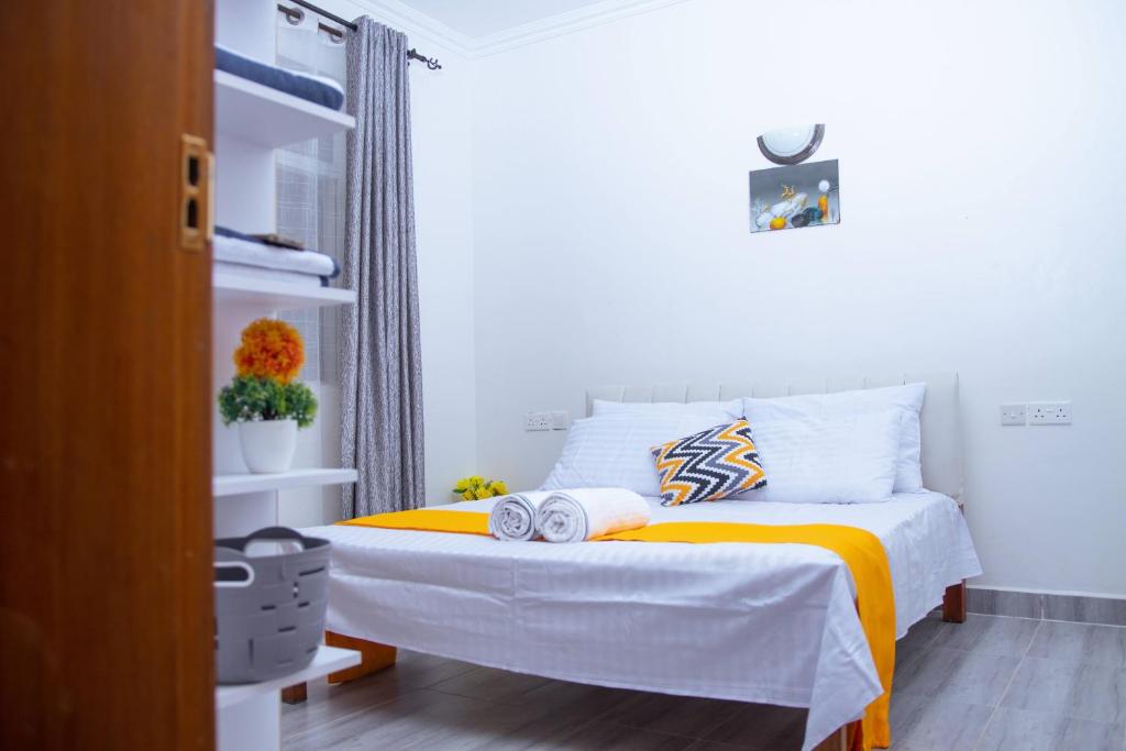 - une chambre avec un lit et une couverture jaune dans l'établissement Kezmo Siloam Paradise, à Mombasa