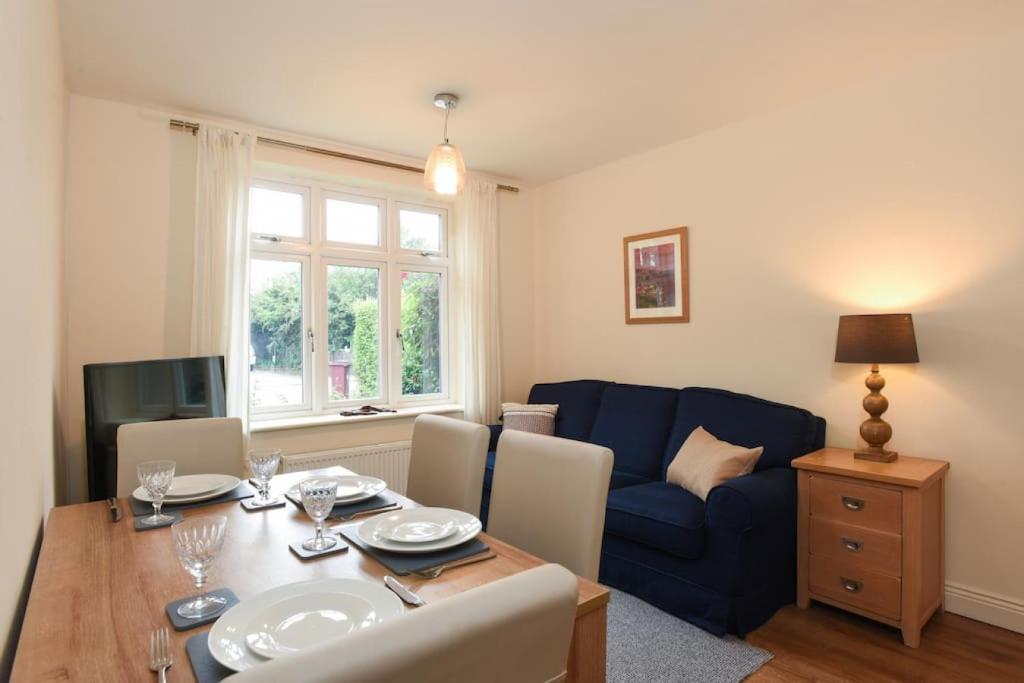 a living room with a table and a blue couch at Cosy One Bed Bungalow Style Annex in Southbourne