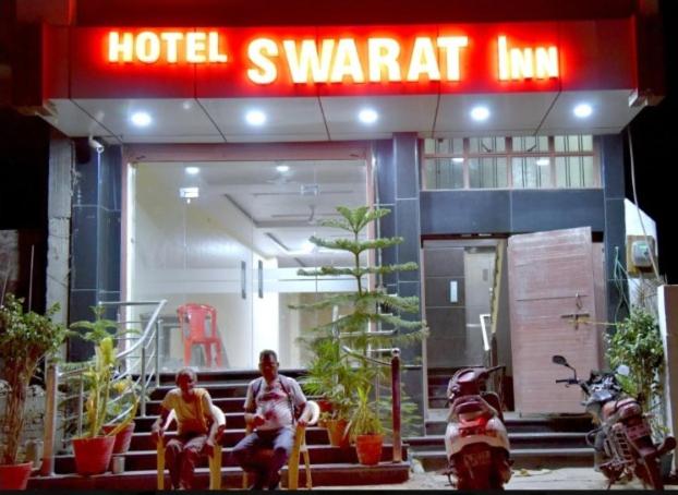 deux hommes assis devant un hôtel singat dans l'établissement Hotel Swarat Inn By BookingCare, à Amarpātan