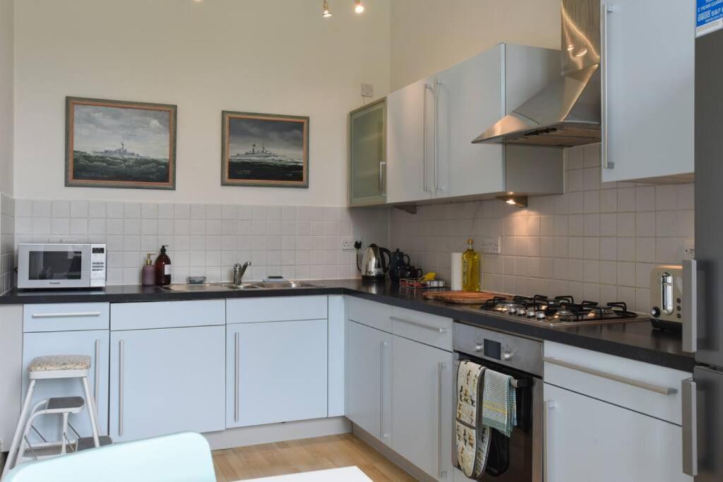 a kitchen with white cabinets and a stove top oven at Naval Officers Quarters Flat in Gosport