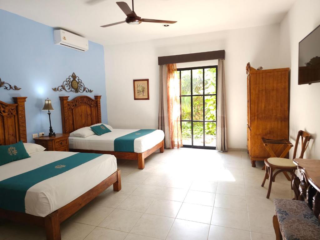 a bedroom with two beds and a table and a window at Hotel Fundadores in Valladolid
