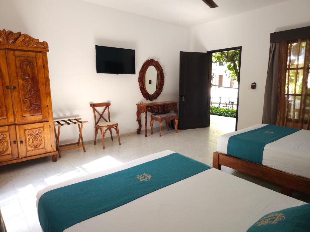 a bedroom with two beds and a dresser and a mirror at Hotel Fundadores in Valladolid