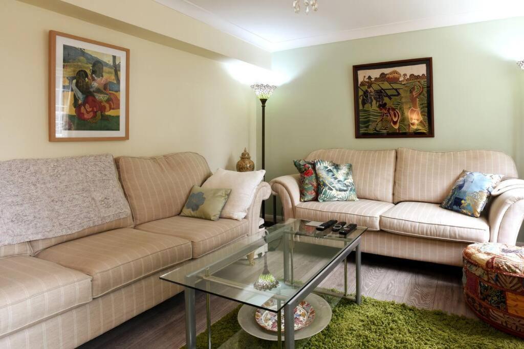 a living room with two couches and a glass table at 4 BR Family Home w parking garden in Emsworth