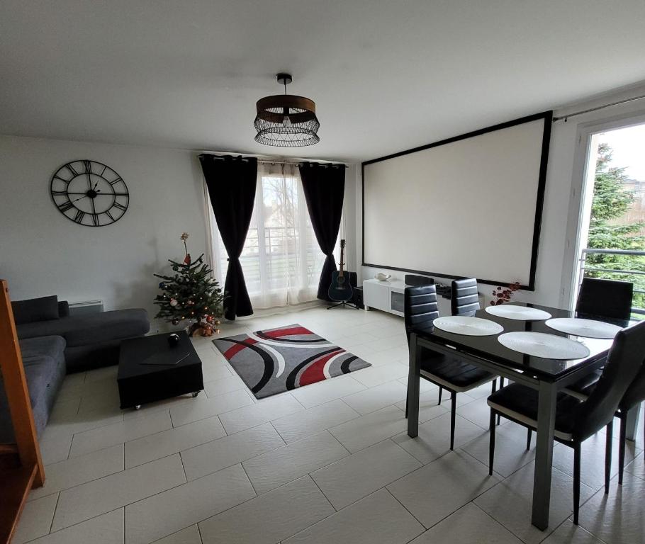 a living room with a table and a screen at Duplex proche Disney avec écran cinéma in Chessy