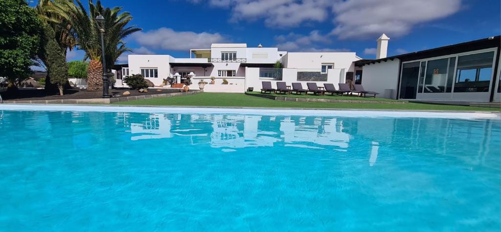 una gran piscina azul frente a una casa en Renovated Villa Mahalo with swimming pool & tennis court en Tías