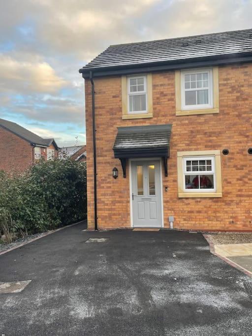 a brick house with a white door and a driveway at Tootle Drive in Longridge