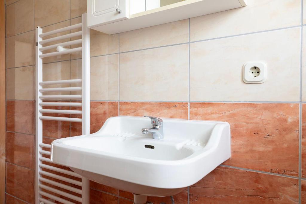 ein Badezimmer mit einem weißen Waschbecken und einem Regal in der Unterkunft Apartman Ana in Kupres