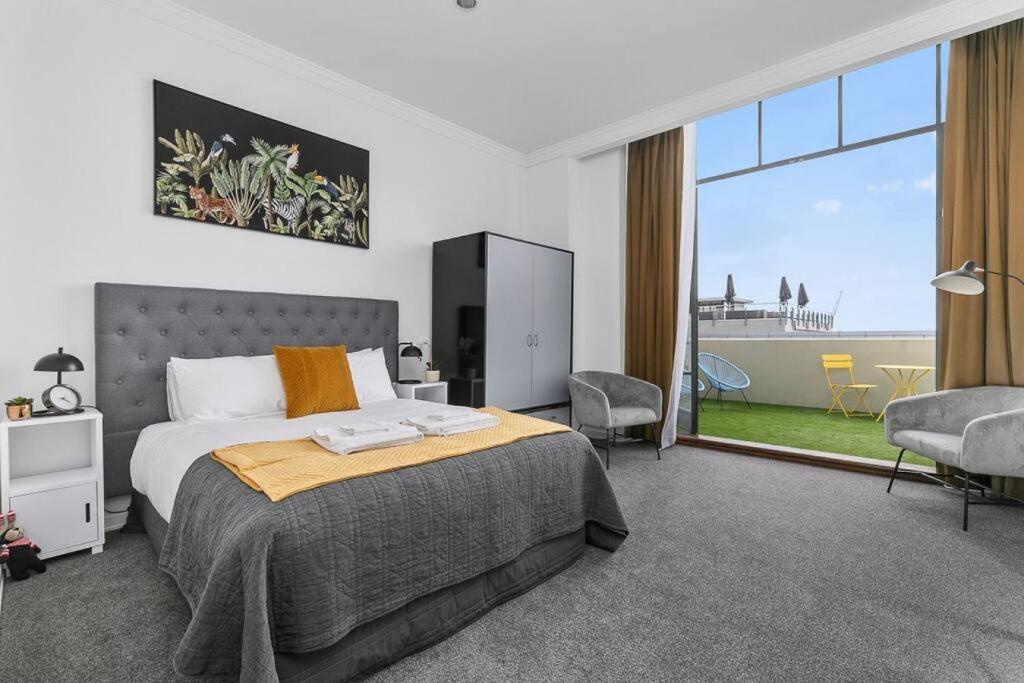een slaapkamer met een bed en een groot raam bij Happy Days in Auckland