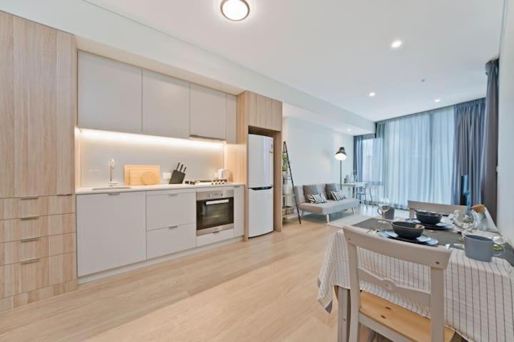 a kitchen with white cabinets and a living room at Stylish 1BR Entire CBD Apt 5 Minutes Train Station in Sydney