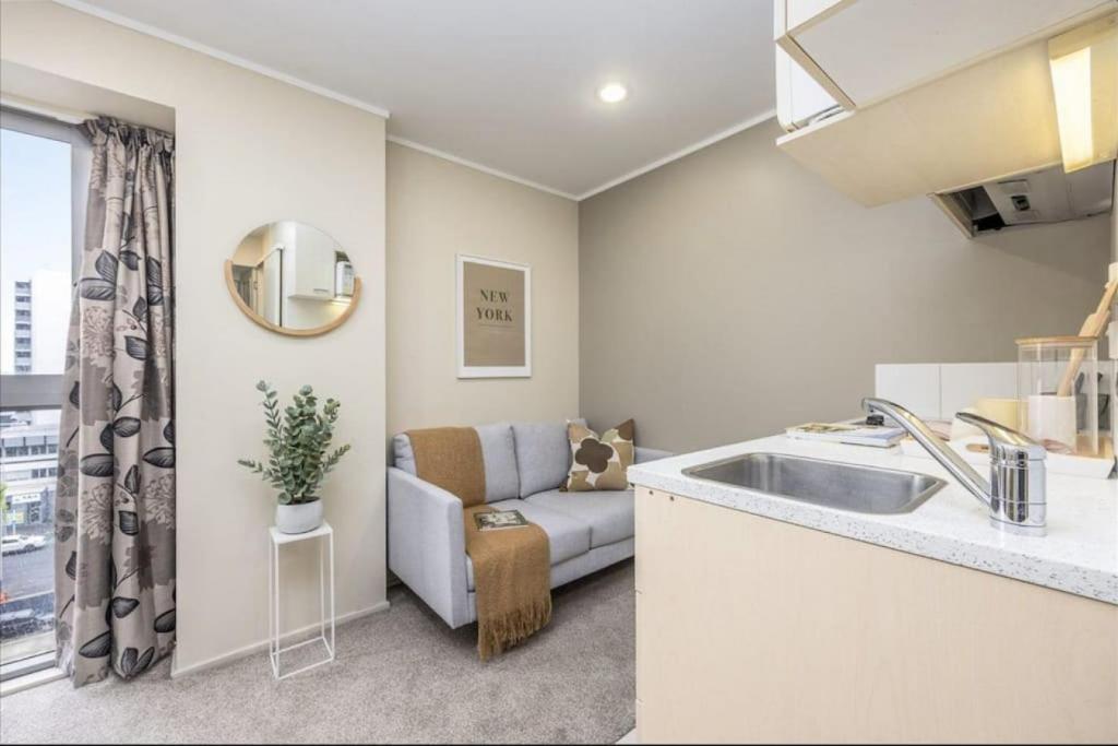 eine Küche und ein Wohnzimmer mit einem Sofa und einem Waschbecken in der Unterkunft Pocket Rocket One Bed Apartment in Auckland