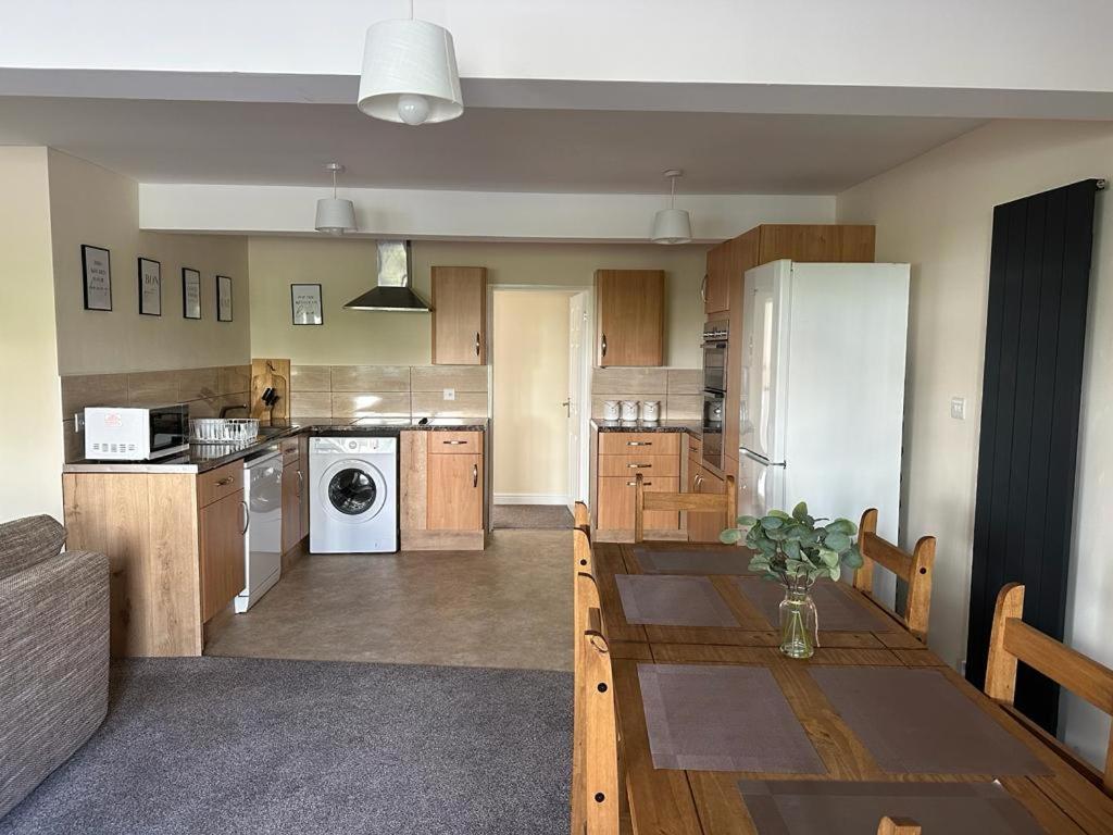a large kitchen with a table and a refrigerator at Yellow Sunflowers Flat In Stroud in Stroud