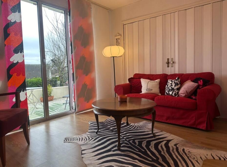 uma sala de estar com um sofá vermelho e uma mesa em Charmante maison 10 mn Center Parcs Ailette em Laon