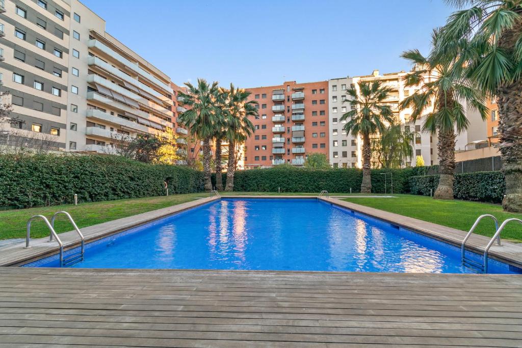 - une piscine bordée de palmiers et de bâtiments dans l'établissement Tendency Apartments 3, à Barcelone