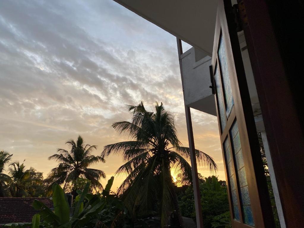 a view of a sunset from a building with palm trees at Sunshine Holiday Home at Wattala in Wattala