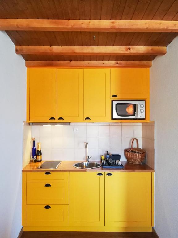 a yellow kitchen with a sink and a microwave at Casa da Praça in Freixo de Numão