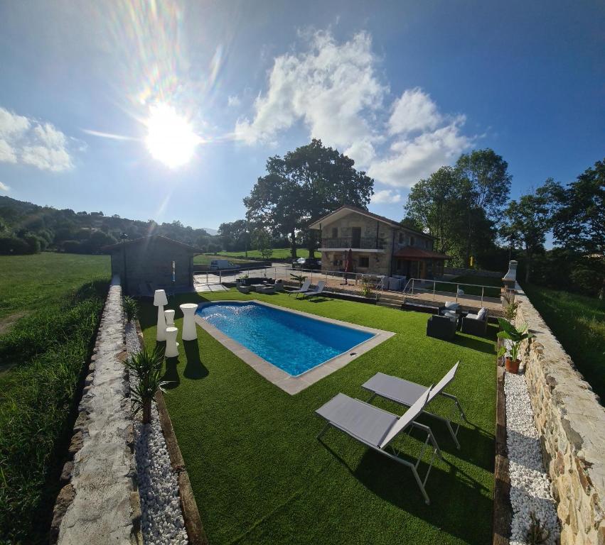 un patio trasero con piscina y una casa en CASA RURAL LALLANTA, en Pedroso