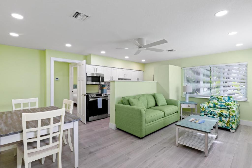 a living room with a green couch and a table at Pirates Cove Cottage at Palm View Inn of Sanibel with Bikes in Sanibel