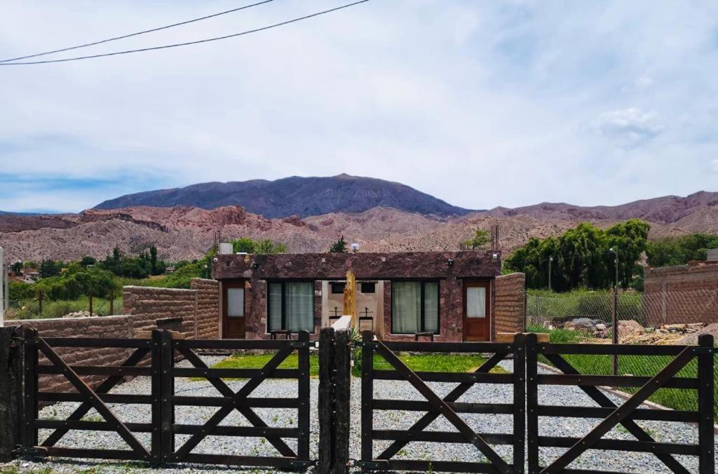 una casa con una valla y montañas en el fondo en Cielos de Maimará en Maimará