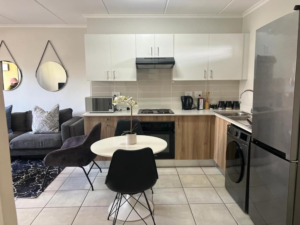 a kitchen with a table and chairs and a couch at Greenpark Apartment in Kempton Park