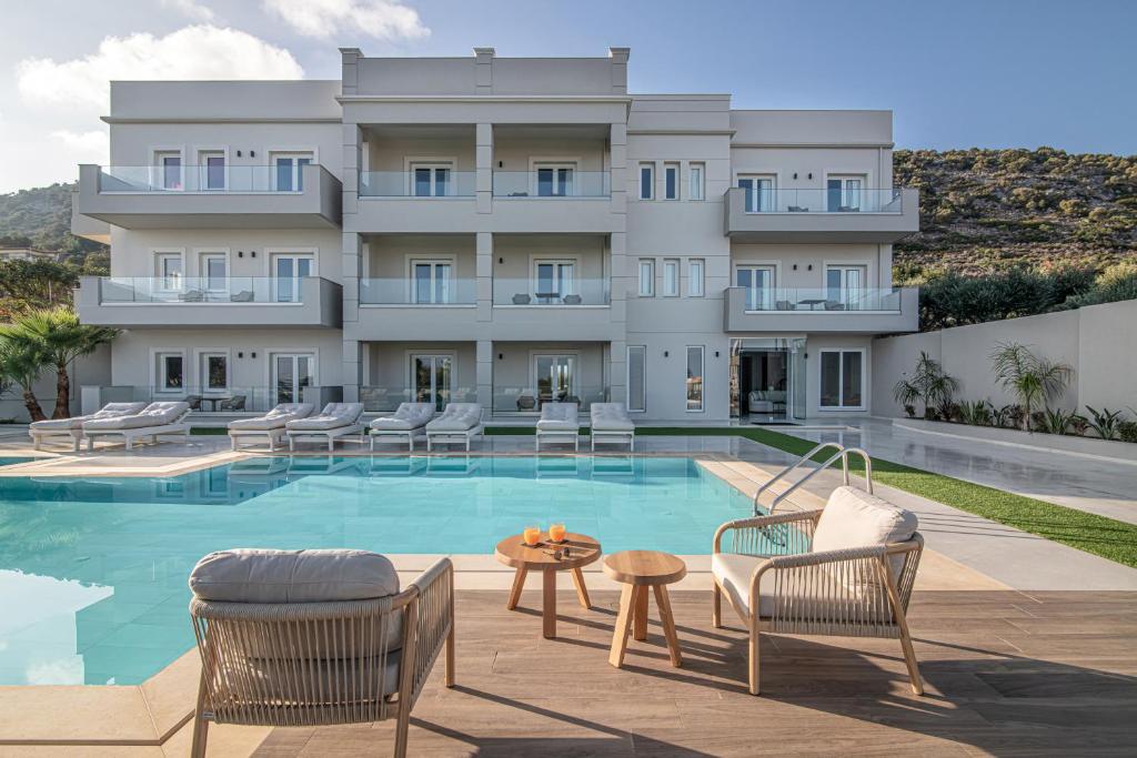 a hotel with a pool and chairs and a building at Filia Luxury Suites in Stalís